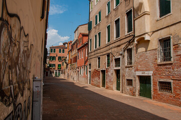 An empty alleyway with brick houses on a clear sunny day in Venice, Italy