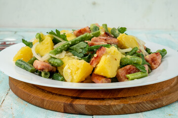 Closeup potato salad with green beans, bacon. Served in a white plate, Belgian or Liege salad.
