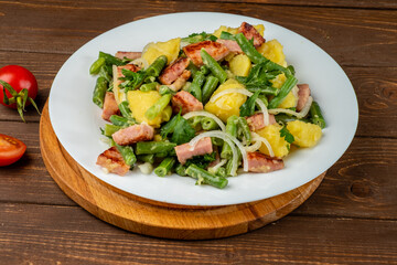 Delicious potato and bean salad, traditional Belgian salad in a white plate on a wooden background.