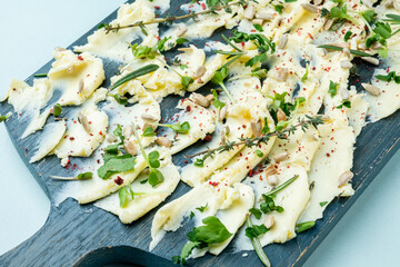 Wooden board with butter and herbs with seeds smeared on it, close-up.