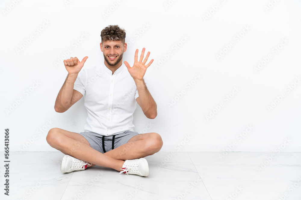 Canvas Prints Young blonde man sitting on the floor isolated on white background counting six with fingers