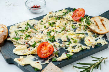 Wooden board with butter, rosemary, thyme, seeds and spices, trendy new snack on white table.