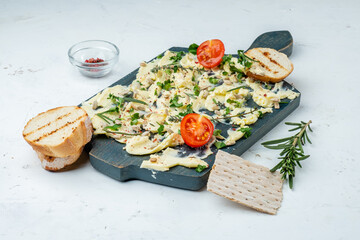 Wooden board with butter, herbs and baguette on white texture background.