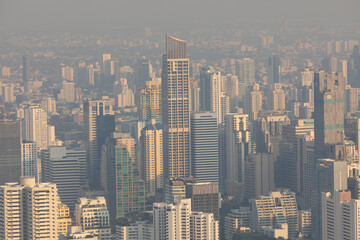 Panoramic view of the skyline of Bangkok, Thailand, at sunset, with its skyscrapers, plunged in pollution, from the observation deck of the Baiyoke Tower II