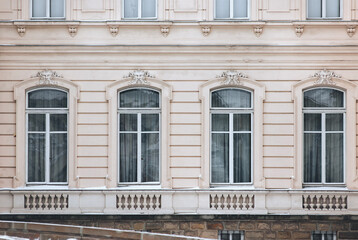 Fototapeta premium Windows with maskaron on the facade of an old house. Beautiful decorative architecture with relief and patterns. Lviv, Ukraine.