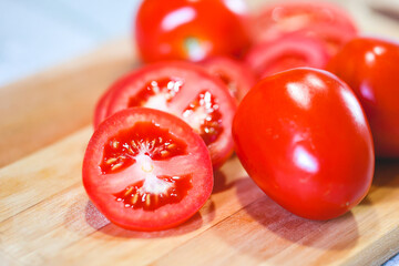 Tomates sobre uma tábua de madeira em fotografia macro. Tomates cortados e tomates inteiros....