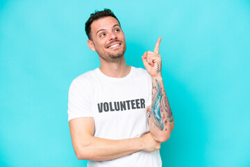 Fototapeta premium Young volunteer caucasian man isolated on blue background pointing up a great idea
