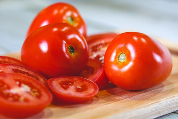Tomates sobre uma tábua de madeira em fotografia macro. Tomates cortados e tomates inteiros....