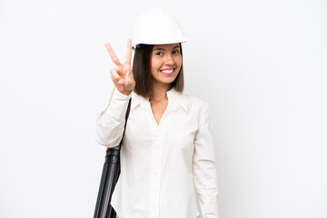 Young architect woman with helmet and holding blueprints isolated on white background smiling and showing victory sign