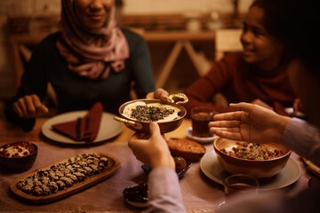 Close up of Middle Eastern family passing food while eating dinner at dining table.