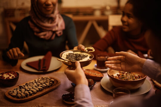 Close Up Of Middle Eastern Family Passing Food While Eating Dinner At Dining Table.