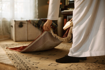 Close up religious Muslim placing prayer mat on floor at home.