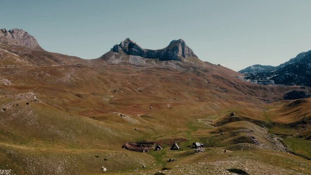 Areal shot over the Durmitor-national park of Montenegro.4K drone shot through the photo frame.Steppe landscape,shepherd settlement and rocky mountains.Picturesque moony and rugged landscape.
