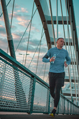 Morning run over the bridge. Fitness, sport and recreation. Sports man jogging and listen the music.