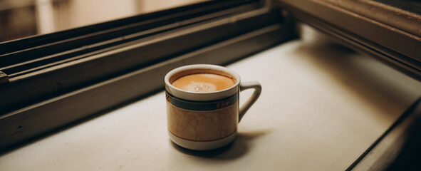 Coffee cup near the window with shutters in Turin, Italy.