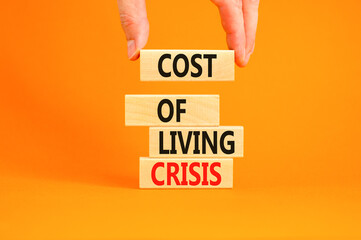 Cost of living crisis symbol. Concept words Cost of living crisis on wooden blocks. Beautiful orange table orange background. Businessman hand. Business cost of living crisis concept. Copy space.