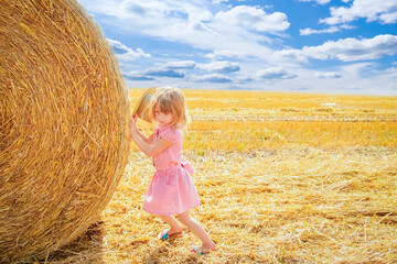 Naklejka na ściany i meble happy child on a field with bales harvest in autumn