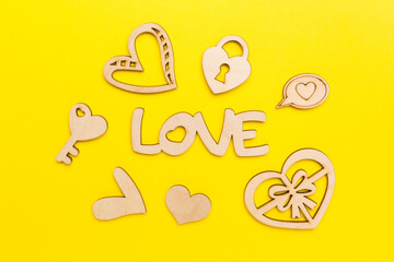Wooden word love with hearts on color background, top view