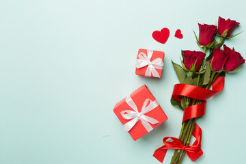 Valentines day gift box with red roses on color background, top view