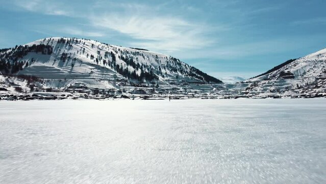 Man walking on frozen lake. lower angle. Image moving towards man.