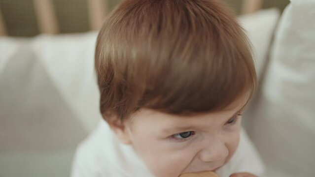 Adorable hispanic toddler sucking toy standing on cradle at bedroom