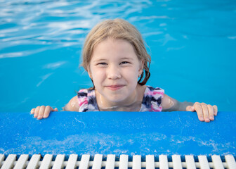 Fototapeta na wymiar Joyful child at edge of swimming pool in summer