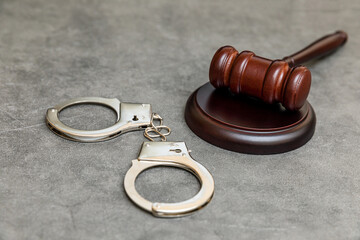 Law theme. Court of law trial in session. Judge gavel handcuffs on grey table in lawyer office or...