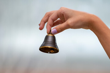 A small bell in the girl's hand on a neutral background, close-up, Concept: the first bell, a...