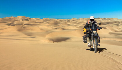 One Motorbiker driving in sand dune desert. Motorcycle Adventure in Namib Desert, Namibia.