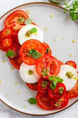 Classic italian salad caprese served in original form with different tomatoes, mozarella, pesto sauce and basil