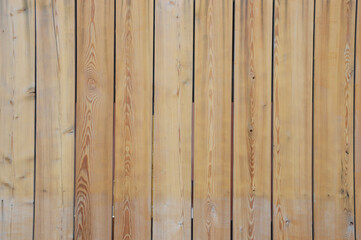 Light brown vertical wooden boards with a natural natural pattern. Background or texture of a wooden wall, fence.