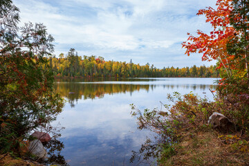 Fototapeta na wymiar Small lake in northern Minnesota with pines birch and maple trees along the shore during autumn