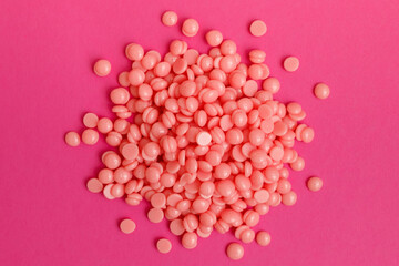 Beautiful pink depilation hot wax granules on magenta background. Depilatory wax. Epilation, depilation, unwanted hair removal. Top view.