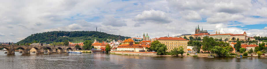 Naklejka na ściany i meble waterfront view across the river Vltava to Castle, Charles Bridge and Petrin Lookout tower, Prague, Czech republic