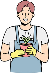 Smiling man gardener holding plant