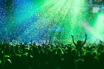 A crowded concert hall with scene stage green lights, rock show performance, with people...