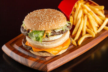 Delicious hamburger with two meats, cheddar cheese, fried egg, sauce and salad. Accompanied by french fries.
