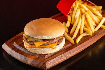 Delicious hamburger with cheddar cheese and pickles. Accompanied by french fries.