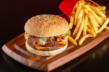 Delicious burger with three meats, cheddar cheese, bacon, sauce and salad. Accompanied by french fries.