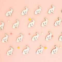 Trendy Easter pattern made with white rabbits and pastel sweets on bright pink background. Minimal...