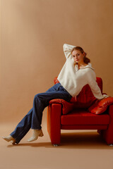 Fashionable confident woman wearing trendy white knitted zip neck sweater, blue wide leg jeans,...