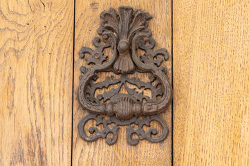 An oild rusted knocker on a wooden door.