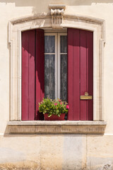 Fototapeta na wymiar Flowers in a red shuttered window.