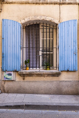 Blue painted shutters on an iron barred window.
