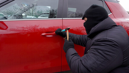 a thief in a black mask, hacks a car, red color