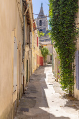 Fototapeta na wymiar Steeple on a small church seen through an alley in Arles.
