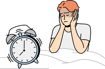 Guy in bed closes ears not to hear sounds of alarm clock.