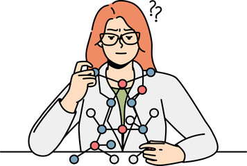 Woman scientist sitting at desk, looks at molecule model.