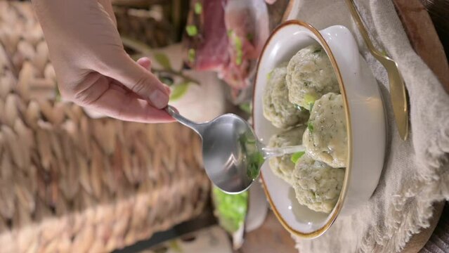 Canederli or Knodel in broth with green onion. North italian traditional dish, typical pasta for Trento, Alps, Alto Adige, Italian, Austrian cuisine. High quality footage vertical 