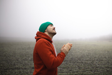 A man in the fog prays to God. Prayer to God. Believer. - obrazy, fototapety, plakaty